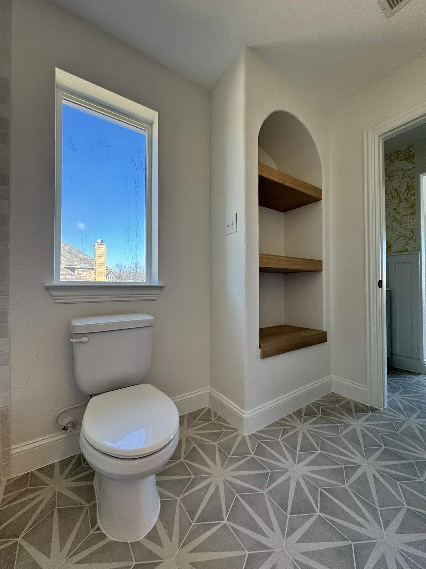 Bathroom with patterned tile floor and arched built-in shelves